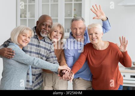 Zufriedene Senioren lächeln zusammen mit gestapelten Händen in der Küche, Freundschaftskonzept Stockfoto