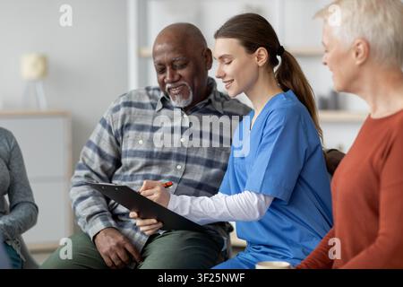 Konzentrierte junge Krankenschwester mit Patient in der Klinik, die den Gesundheitsplan bespricht, Gesundheitskonzept Stockfoto