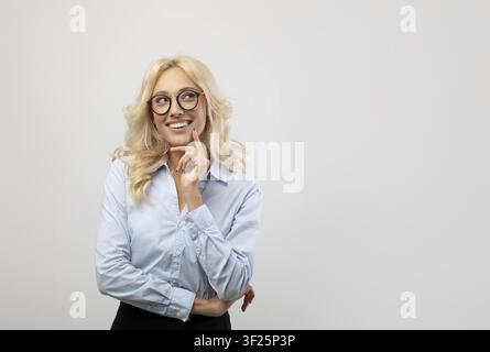 Lächelnde junge kaukasische Frau mit Brille, die im Büro nachdenkt, Geschäftskonzept Stockfoto