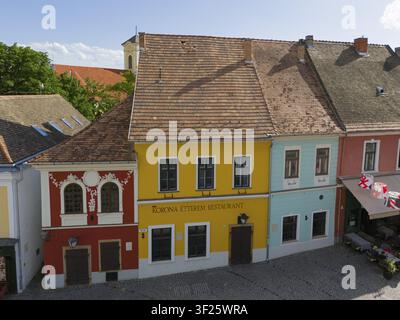 Historische Straßenszene mit farbenfrohen Gebäudefassaden und einem zentral gelegenen Restaurant, Luftaufnahme, farbenfrohe Häuser auf dem Hauptplatz Fo ter, Sze Stockfoto