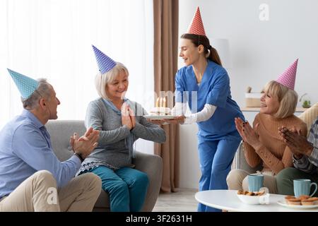 Zufriedene ältere kaukasische Frau feiert Geburtstag mit Kuchen zu Hause, Gesundheitskonzept Stockfoto