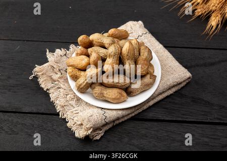Gekochte Erdnüsse in der Schale auf Keramikplatte, traditioneller chinesischer rustikaler Snack Stockfoto