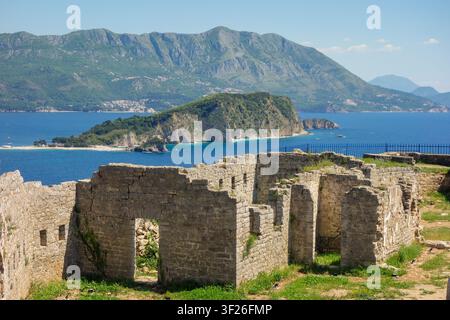 Ruinen des alten Forts Mogren in Budva, Montenegro. Die Insel Sveti Nikola im Hintergrund. Stockfoto