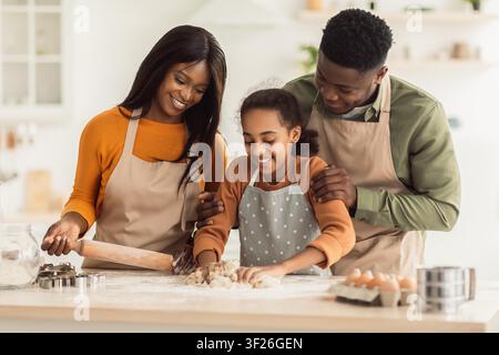 Glückliche schwarze Familie kocht zusammen in einer modernen Küche und macht Kekse Stockfoto