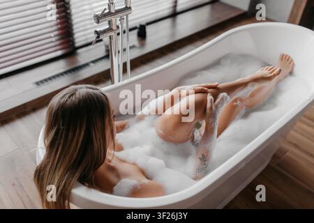 Unerkennbare Frau entspannt sich in der Badewanne mit Blasen, Spa-Konzept Stockfoto