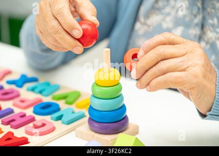 Alzheimer-Krankheit AD, asiatische ältere Frau mit Demenz lernen praktische motorische Fähigkeiten Rehabilitation. Stockfoto