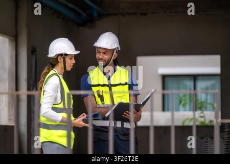 Zwei Bauleiter halten Tablet und Klemmbrett auf der Wohnbaustelle, inspizieren unvollendete Wohngebäude im Inneren, Hous Stockfoto