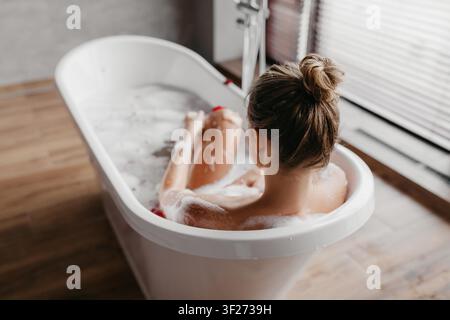 Frau genießt entspannendes Schaumbad in modernem Badezimmer, nicht zu erkennen. Spa-Konzept Stockfoto