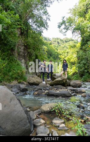 Gruppe von jungen Asiaten, die auf dem Felsen stehen, während sie in der tropischen Natur wandern und trekken Stockfoto