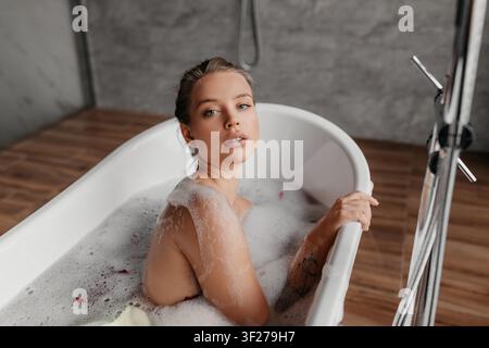 Junge Frau entspannt sich in der Badewanne mit Blasen, Spa-Konzept Stockfoto