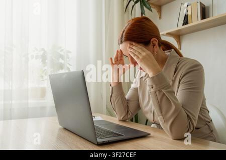 Frau leidet unter Kopfschmerzen und Arbeits burnout. Müdigkeit, Stress und Erschöpfung nach der Arbeit an einem Computer, Frauengesundheit Stockfoto