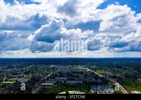Luftbild der Stadt Jelgava, Lettland, mit Wohnblocks, Grünflächen und umgebenden Wäldern unter einem weiten blauen Himmel mit d Stockfoto