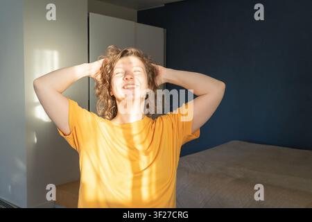 Junge Frau genießt das Morgenlicht im Schlafzimmer Stockfoto