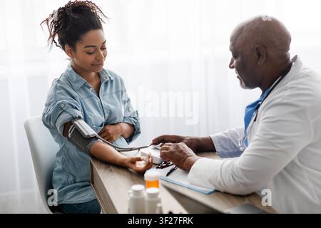 Schwarze Frau, deren Blutdruck von einem Arzt in einer Klinik gemessen wird, Gesundheitskonzept Stockfoto