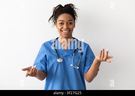 Lächelnde schwarze Krankenschwester in OP-Kleidung mit Stethoskop in der Klinik, Gesundheitskonzept Stockfoto