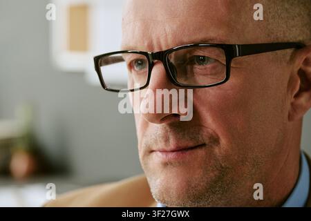Porträt eines mittelalten männlichen Therapeuten im Krankenhaus, der über Genesung nachdenkt Stockfoto