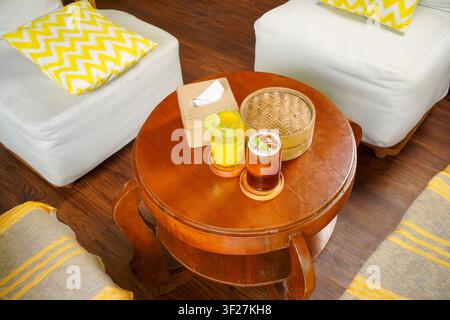 Zwei erfrischende gekühlte Getränke mit Zitrone und Minze, serviert auf einem Holztisch in einer gemütlichen Café-Atmosphäre mit natürlichem Licht und Gartenblick, perfekt für den Sommer Stockfoto