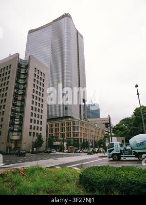 Moderner Glaskoloss, der über einer Straßenkreuzung in Yurakucho, Chiyoda, Tokio, Japan an einem bewölkten Tag aufragt Stockfoto