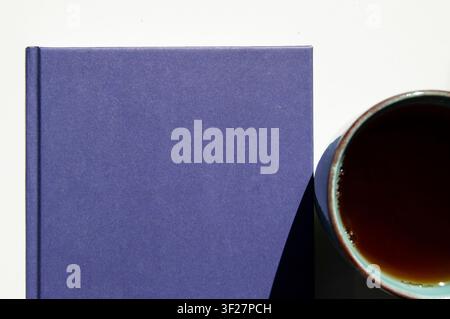 Eine Tasse schwarzer Tee und ein leeres Buch. Leeres Buch mit Kopierraum. Ein Tagebuch und eine Tasse Tee isoliert. Stockfoto