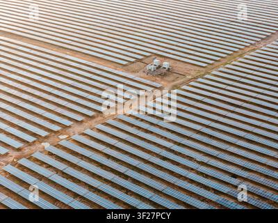 Drohnenansicht einer großflächigen photovoltaischen Solarstromanlage mit Tausenden von Solarmodulen, die in geometrischen Mustern angeordnet sind. Stockfoto