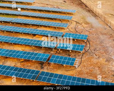 Drohnenblick auf ein Solarfeld mit Stromkabeln an einer Anlage für erneuerbare Energien Stockfoto