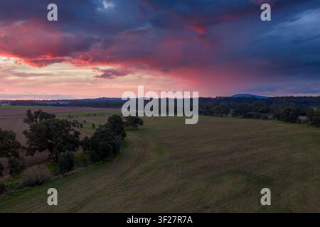 Luftbild eines dramatischen farbenfrohen Sonnenuntergangshimmels über Farmland und fernen Bergen in Newstead in Central Victoria, Australien Stockfoto