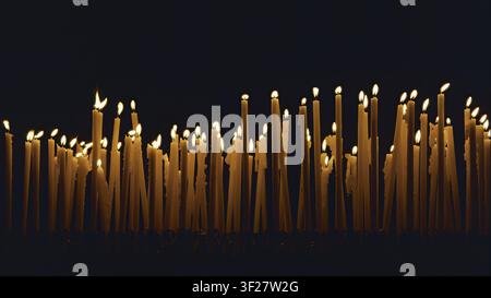 zahlreiche Votivkerzen, die in einer Kirche angezündet sind, ein Symbol der Hingabe Stockfoto