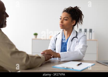 Junge schwarze Ärztin berät mit Patientin in der Arztpraxis, konzentrierter Ausdruck Stockfoto