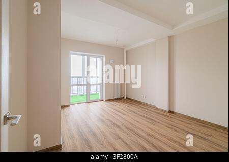 Leerer Raum mit Holzboden, beigen Wänden und einem Balkon. Hell und sauber Stockfoto