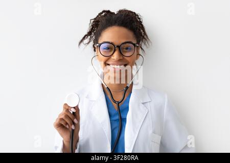 Lächelnde schwarze Ärztin mit Stethoskop in der Klinik, Gesundheitskonzept Stockfoto
