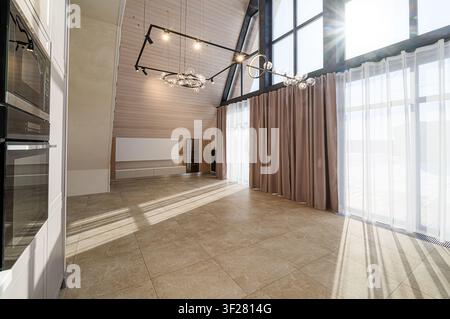 Helle Innenräume, die moderne Designelemente zeigen: hohe Decken, große Fenster, stilvolle Beleuchtung und neutrale Töne Stockfoto