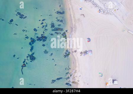 Luftaufnahme von oben: sanfte türkisfarbene Meereswellen küssen einen sandigen Strand Stockfoto