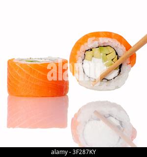 Essstäbchen halten eine Lachs-Avocado-Sushi-Rolle Stockfoto