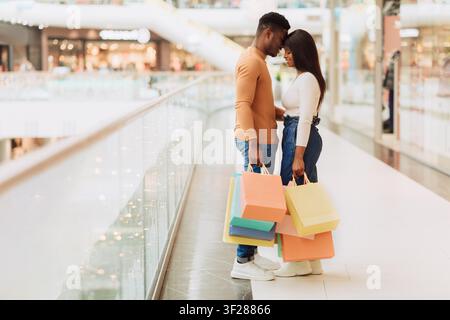 Paar hält Einkaufstüten in der Einkaufsmall, lächelt und verbringt Zeit zusammen Stockfoto