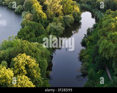 Luftaufnahme des Maschsees in Hannover, mit üppigen grünen Bäumen, die die Ufer säumen, und zwei Personen, die auf Stand-Up-Paddleboards im ruhigen Wasser paddeln, Hannover Stockfoto