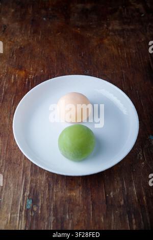 Zwei rosa und grüne traditionelle japanische Mochi oder asiatische Wagashi, Reiskuchen. Leckere Süßigkeiten, Dessert auf braunem Holz-Hintergrund. Oberansicht, Kopierplatz Stockfoto