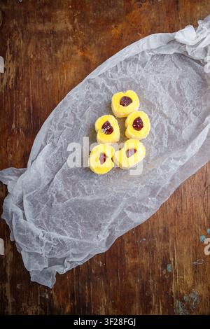 Türkische Delikatesse, gelbe Lokumrolle mit Gelee und Kokosflocken auf weißem Papier, hölzerner Hintergrund. Östliche Süßigkeiten, orientalisches Essen. Traditionell lecker d Stockfoto