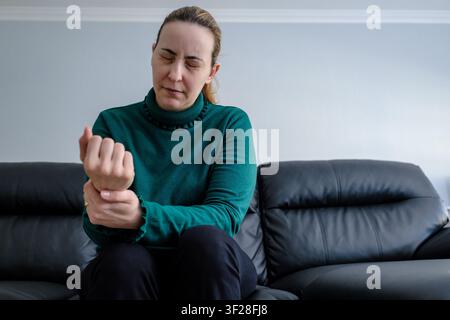 Frau, die ihr schmerzendes Handgelenk hält, das an Karpaltunnelsyndrom oder Arthritis leidet Stockfoto