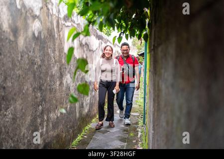 Fröhliches junges Paar erkundet eine schmale städtische Gasse während des Urlaubs in Yogyakarta, Indonesien. Stockfoto