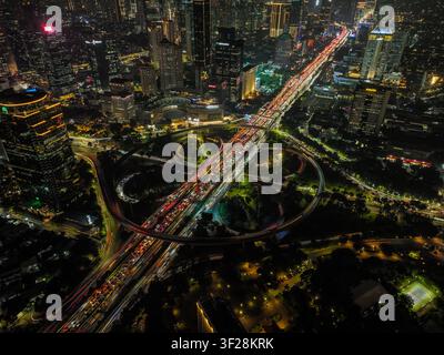 Luftaufnahme der beleuchteten Semanggi-Brücke bei Nacht mit starken Lichtspuren des Verkehrs auf der Kleeblatt-Anschlussstelle, umgeben von Wolkenkratzern in Ta Stockfoto