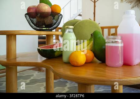 Gesunde Früchte und farbenfrohe Getränke, arrangiert auf einem modernen Holztisch in einem stilvollen Wohninterieur, symbolisieren Frische und ausgewogene Ernährung. Stockfoto