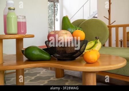 Obstkorb gefüllt mit frischen Produkten neben gesunden Getränken auf einem Holzkaffeetisch. Wellness- und Ernährungsconcept. Stockfoto