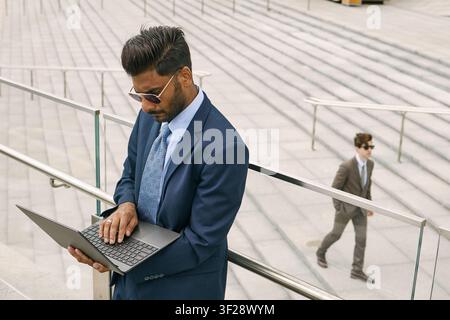 Indischer Geschäftsmann verwendet einen Laptop während des städtischen Arbeits pendels Stockfoto