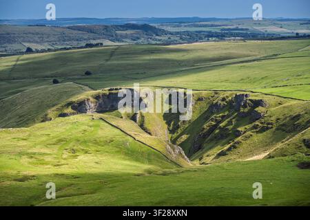 Ein erhöhter Blick hinab in die dramatische Kalksteinklamm von Winnats Pass, umgeben von grünen Feldern und trockenen Steinmauern in Derbyshire, UK Stockfoto