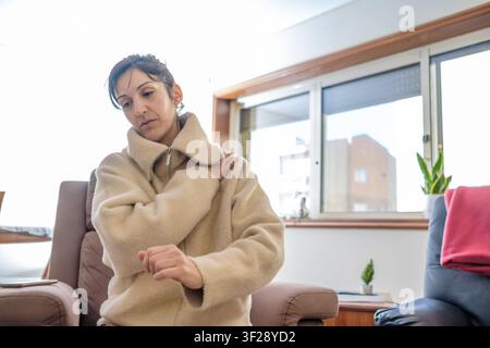 Frau mit Schulterschmerzen, die ihre schmerzende Schulter mit einem schmerzhaften Gesichtsausdruck hält Stockfoto
