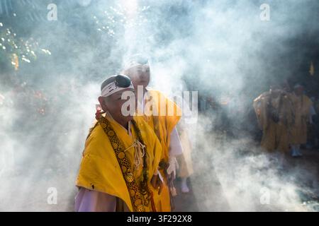 Yamabushi-Mönche, umgeben von dichtem Rauch, nehmen an der Feuerlauf-Zeremonie im Daisho-in-Tempel auf der Miyajima-Insel in Japan teil. Stockfoto