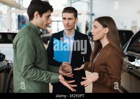 Zwei Männer und eine Frau, die in einem Autohaus verhandeln, Geschäftskonzept Stockfoto