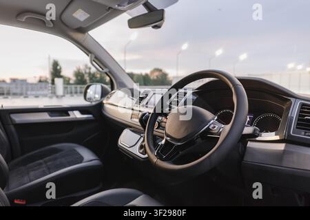Interieur eines Rechtslenker-Vans mit Stoffsitzen. Minivan-Cockpit-Breitwinkelansicht von der Fahrerseite: Sitze, Lenkrad, Armaturenbrett und Mittelkonsole Stockfoto