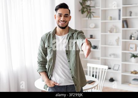 Lächelnder hispanischer Mann, der zu Hause die Hand zur Begrüßung ausstreckt, Geschäftskonzept Stockfoto
