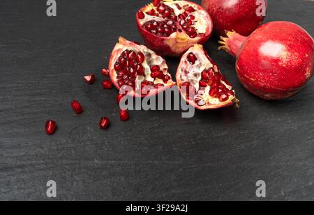 Granatapfel, Rote Reife Ganze Fruchtgruppe, Grenadinen-Zutaten-Frische Süße Bio-Granatäpfel auf Natürlichem Schwarzem Stein-Hintergrund Stockfoto